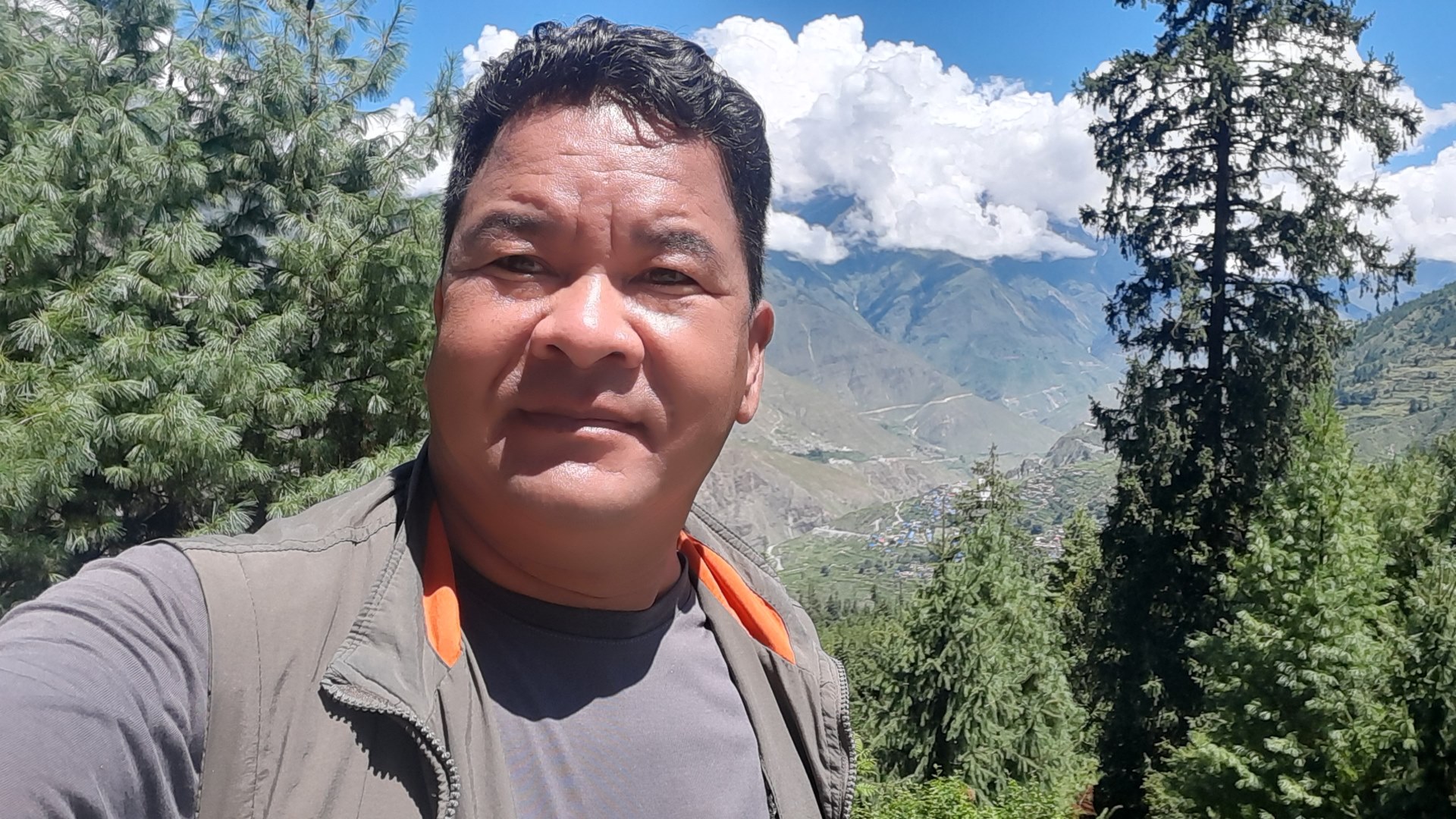 Govinda taking a selfie in front of a hilly landscape